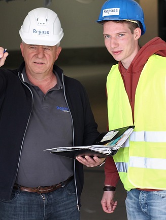 Foto von zwei Personen mit Schutzhelmen und Arbeitskleidung