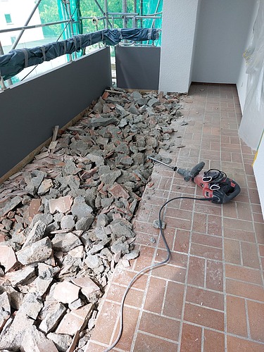 Foto von einem Balkon auf dem der Bodenbelag mit Abbruchhammer entfernt wird