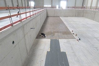 Foto von einer Person kniend am Arbeiten in einer Halle