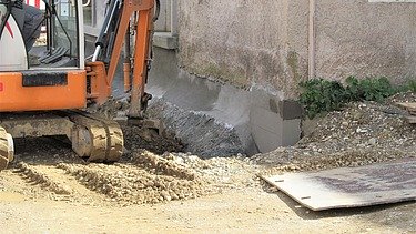 Foto von einem Bagger vor einer Hauswand