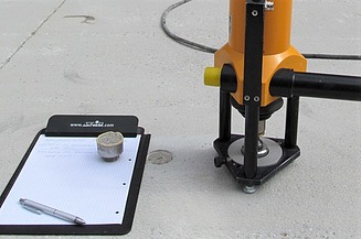 Foto von einem Klemmbrett und Messapparatur für betontechnologische Untersuchungen