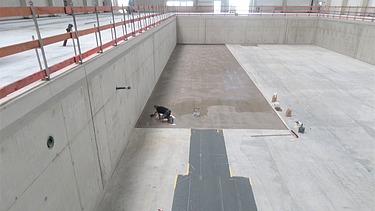 Foto von einer Person kniend am Arbeiten in einer Halle