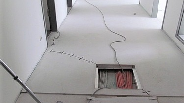 Foto von einem Gang mit einer Bodenöffnung und Kabel