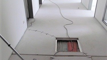 Foto von einem Gang mit einer Bodenöffnung und Kabel