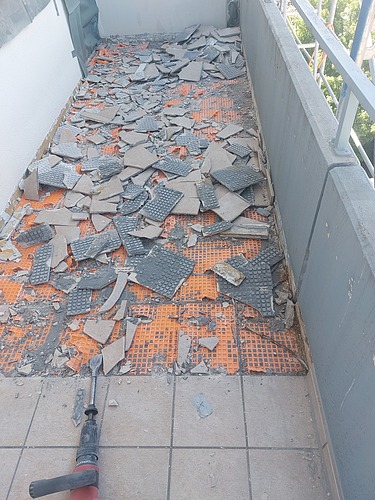 Foto von einem Balkon auf dem der Bodenbelag mit Abbruchhammer entfernt wird