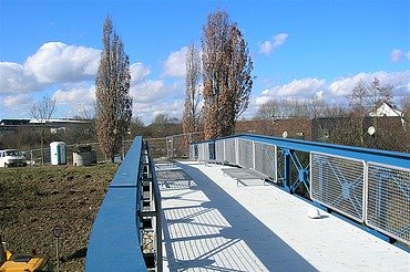 Korrosionsschutz und Brückensanierung Foto von einer Stahlbrücke vor zwei Bäumen