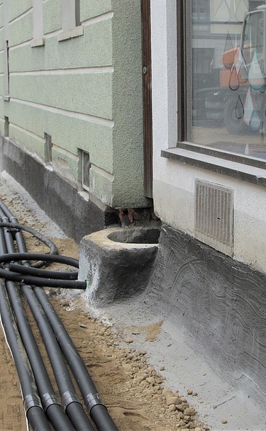 Drainage Foto von schwarzen Drainagerohren vor einem Fundament
