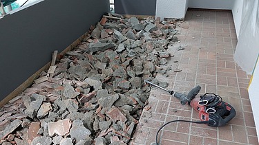 Foto von einem Balkon auf dem der Bodenbelag mit Abbruchhammer entfernt wird