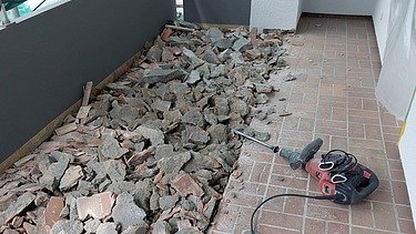 Foto von einem Balkon auf dem der Bodenbelag mit Abbruchhammer entfernt wird