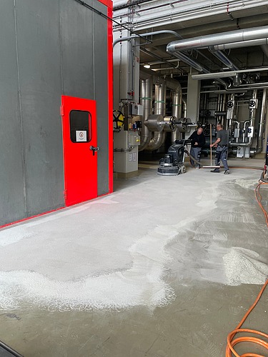 Foto von zwei Mitarbeitern die einen Raum entschichten und schleifen