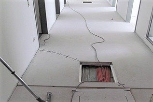 Foto von einem Gang mit einer Bodenöffnung und Kabel